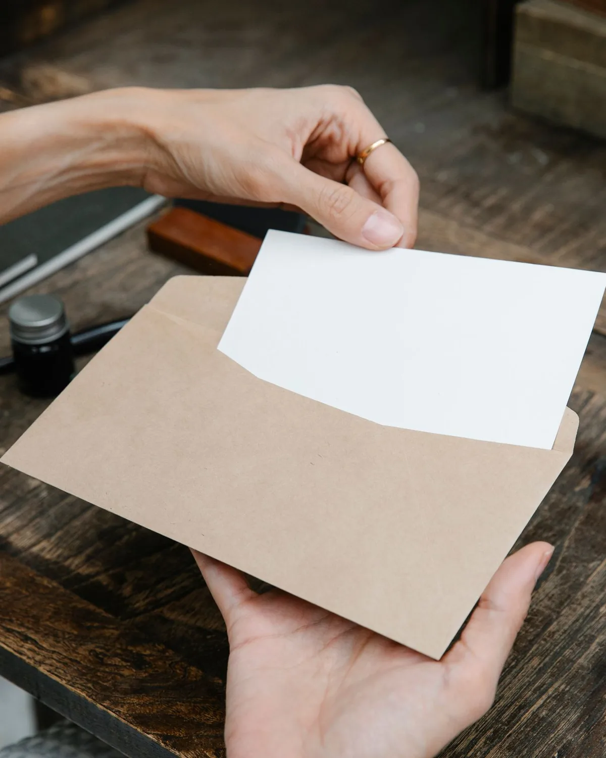 Une lettre qu’on sort de son enveloppe, sur un bureau en bois