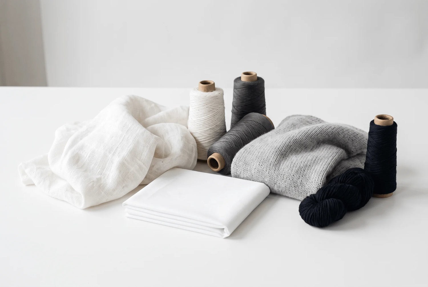 Fibres naturelles de lin, coton et laine présentées sur une table blanche